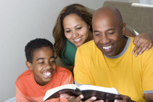 Happy African American family reading The Bible.