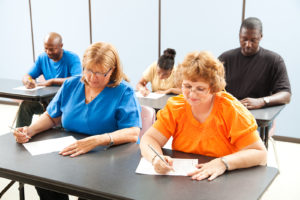 Diverse adult education or college class taking a test.