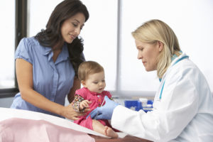 Doctor en cirugía aplicando inspección a una bebe