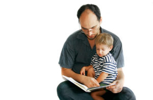 father reading a book to his son over white