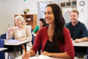 Mujer hispana mira hacia arriba mientras estudia en una clase de educación para adultos