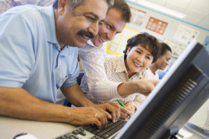 Professor ajudando alunos adultos em terminais de computadores