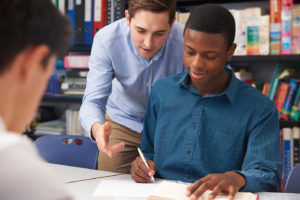 Male Teacher Helping Male Pupil In Class