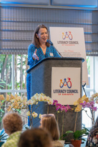Speaker presenting at podium with event signage visible during the Literacy Matters Luncheon.