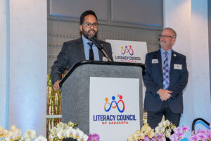 Speaker presenting at podium with event signage visible during the Literacy Matters Luncheon.