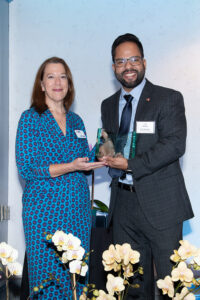 Award recipient standing on stage holding recognition plaque during the Literacy Matters Luncheon.