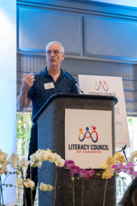 Volunteer of the Year recipient smiling on stage after receiving award at the Literacy Matters Luncheon.