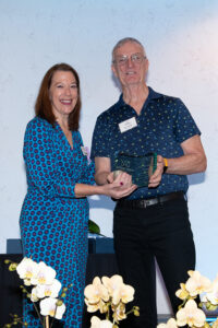 Award recipient standing on stage holding recognition plaque during the Literacy Matters Luncheon.
