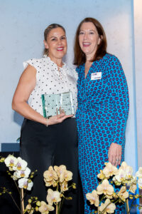Award recipient standing on stage holding recognition plaque during the Literacy Matters Luncheon.