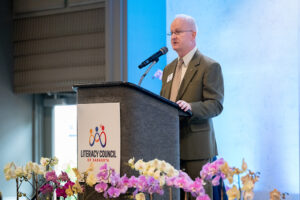 Presenter delivering remarks during the Literacy Matters Luncheon while audience listens attentively.