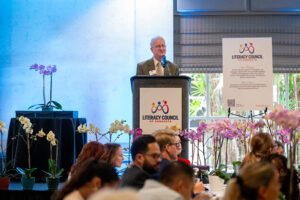 Presenter delivering remarks during the Literacy Matters Luncheon while audience listens attentively.