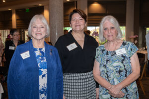 Three attendees smiling and posing together at the Literacy Matters Luncheon.