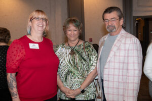 Three attendees smiling and posing together at the Literacy Matters Luncheon.
