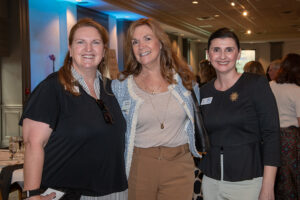 Three attendees smiling and posing together at the Literacy Matters Luncheon.