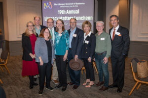 Group of attendees smiling and posing together at the Literacy Matters Luncheon.