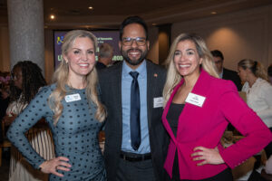 Three attendees smiling and posing together at the Literacy Matters Luncheon.