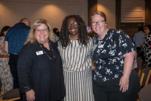 Three attendees smiling and posing together at the Literacy Matters Luncheon.