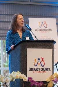 Speaker presenting at podium with event signage visible during the Literacy Matters Luncheon.