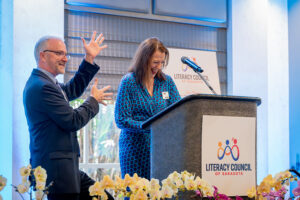 Speaker presenting at podium with event signage visible during the Literacy Matters Luncheon.